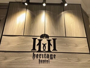 A wooden sign with the text "heritage hostel" and a decorative element above the letters "H&H". - Heritage Hostel (Cairo)