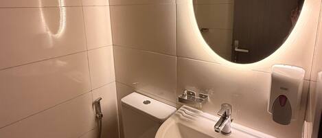 Un baño con inodoro, lavabo, espejo y secamanos.