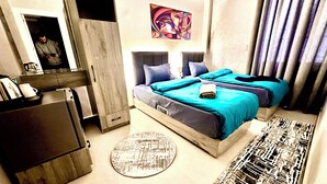 Ein modernes Hotelzimmer mit Bett, Schreibtisch, Kleiderschrank, einem runden Teppich und einem Bild an der Wand.