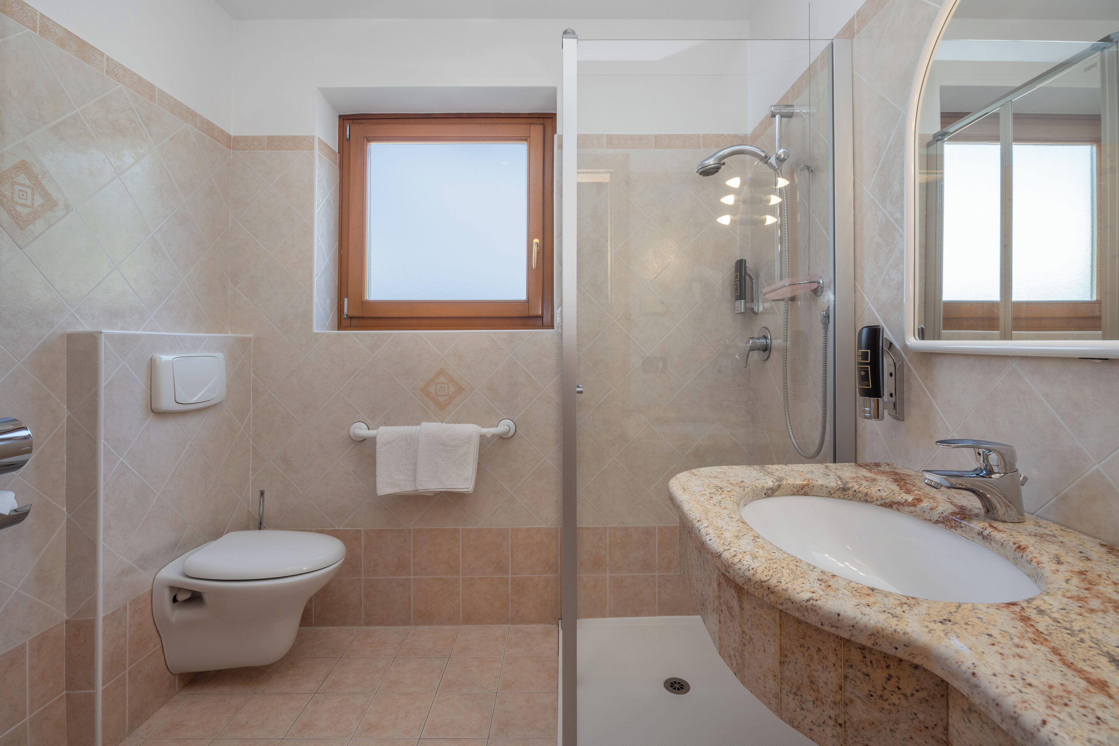 A bathroom with a toilet, a sink, a shower, and a window.
