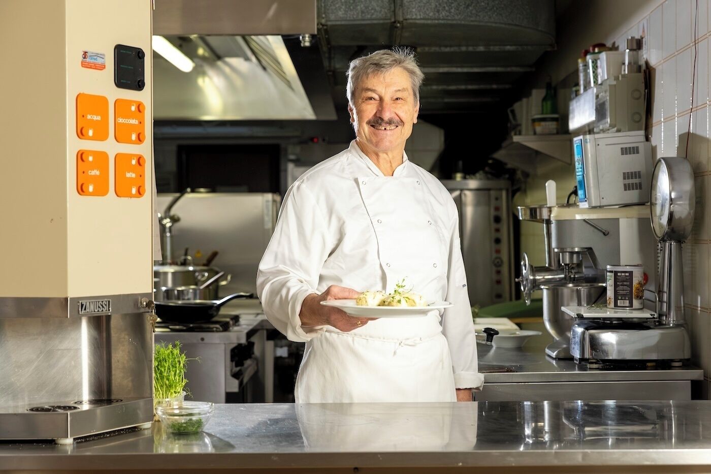 Un chef en una cocina profesional sosteniendo un plato de comida.
