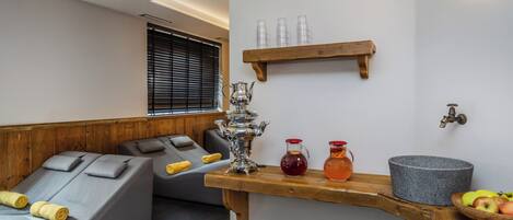 Un moderno cuarto de spa con un banco de madera, un lavabo de piedra y un estante con botellas.