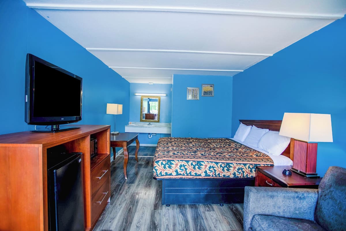Ein Hotelzimmer mit Bett, Fernseher, Schreibtisch und Stuhl.