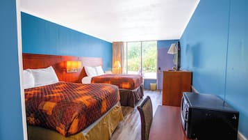 A hotel room with two beds, a desk, a chair, and a suitcase.