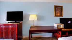 Une chambre d’hôtel équipée d’un téléviseur à écran plat, d’une lampe, d’un four à micro-ondes et d’un tableau encadré au mur.