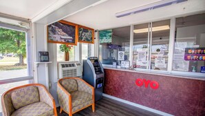 Un espace d’accueil avec deux fauteuils à motifs, un distributeur automatique et un comptoir arborant la marque « OYO ».