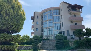 A multi-story building with a curved facade, large windows, and a stone staircase leading to the entrance. - Lukas Hotel (Xhafzotaj)