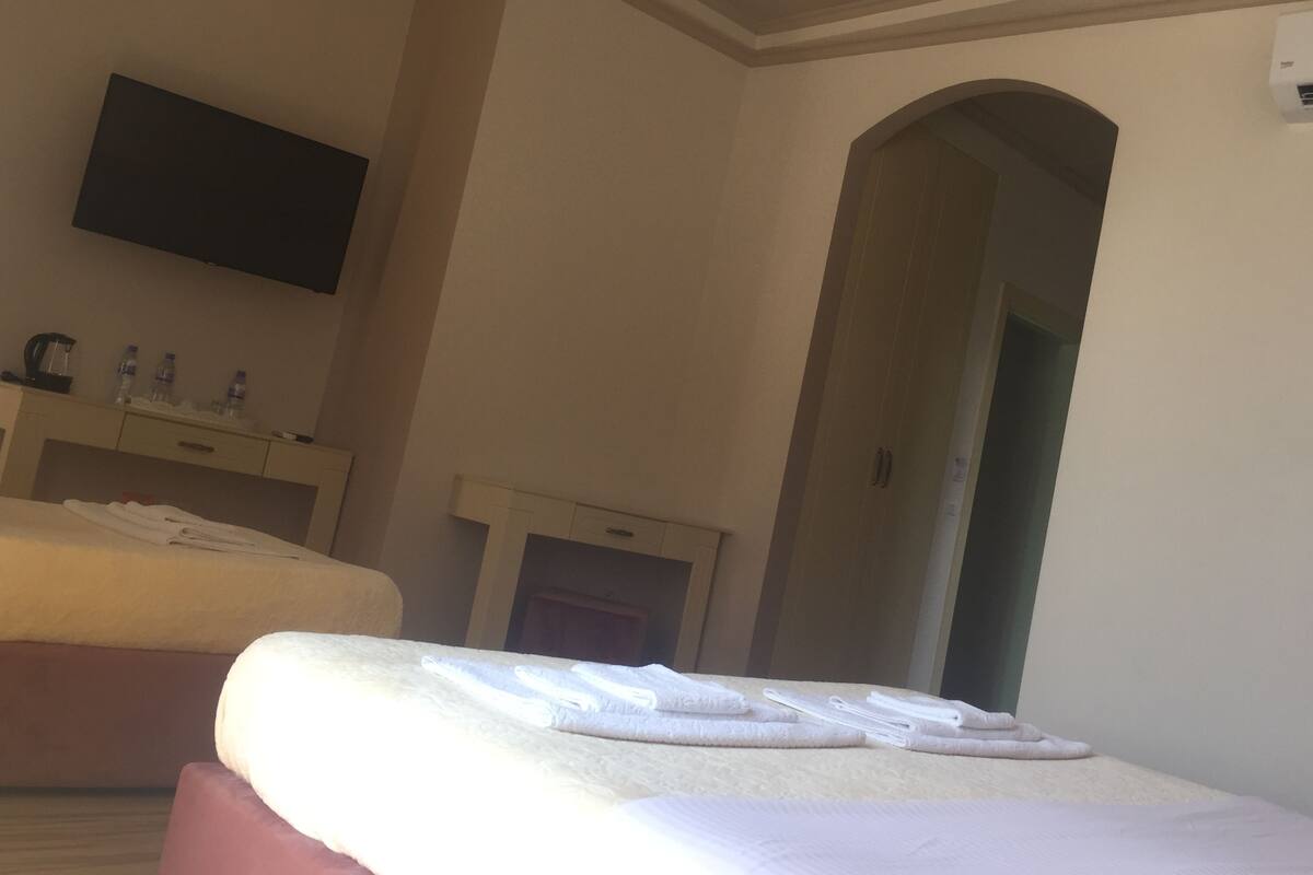 A hotel room with a bed, a TV mounted on the wall, a bathroom with a shower, and a towel rack.