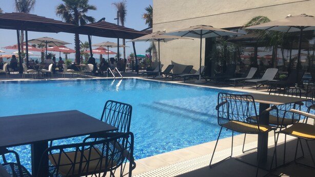 A pool area with lounge chairs and umbrellas. - Lukas Hotel (Xhafzotaj)