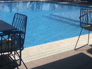 A swimming pool with two black metal chairs and a table. - Lukas Hotel (Xhafzotaj)