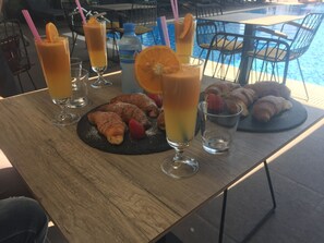 A table with croissants, orange juice, and a bottle of water. - Lukas Hotel (Xhafzotaj)