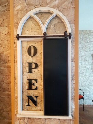 A sign with the word "OPEN" in large letters, mounted on a stone wall with a decorative arch above it. - Casa 44 (Alhaurin el Grande)