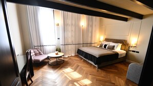 Una habitación de hotel con una cama grande, un sofá, una mesita redonda y una silla.