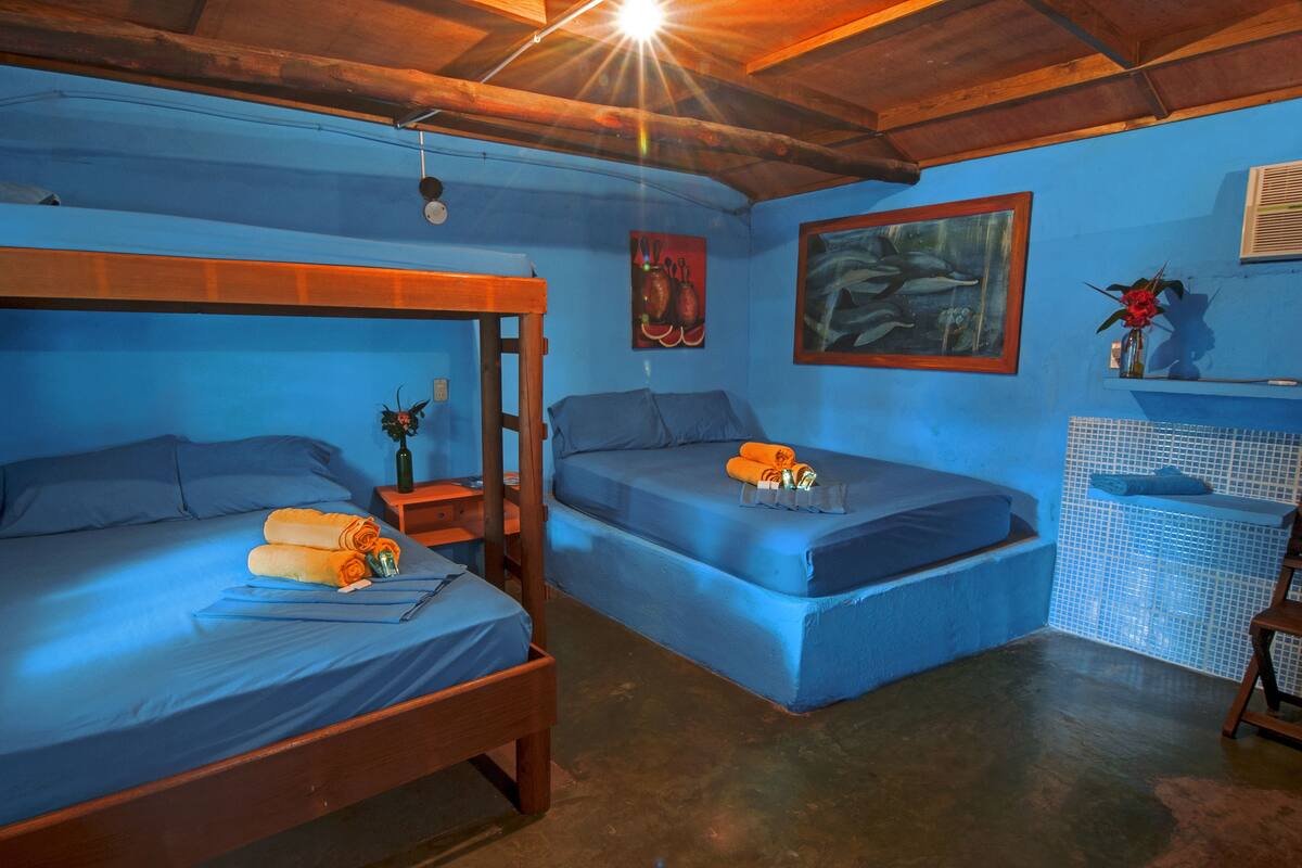 A room with two bunk beds, a small table with a bottle, and a painting on the wall.