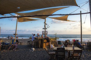 Eine Strandbar mit Holzmöbeln und einem Reetdach.