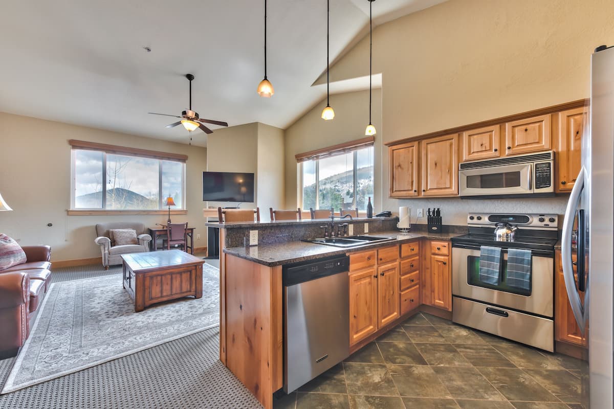 A spacious kitchen with wooden cabinets, a stainless steel dishwasher, a double oven, and a microwave.
