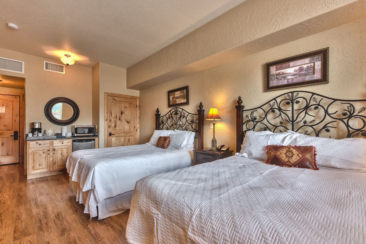 A hotel room with two beds, a wooden cabinet, a microwave, and a coffee maker.