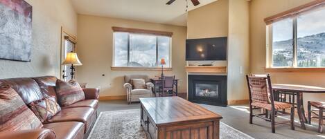 A spacious living room with a leather sofa, a wooden coffee table, a fireplace, and a television.
