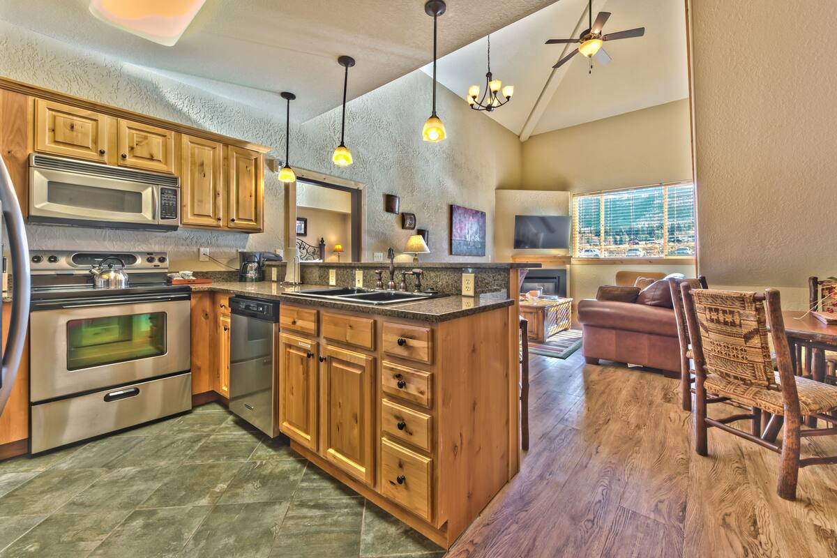 A kitchen with wooden cabinets, stainless steel appliances, and pendant lighting.