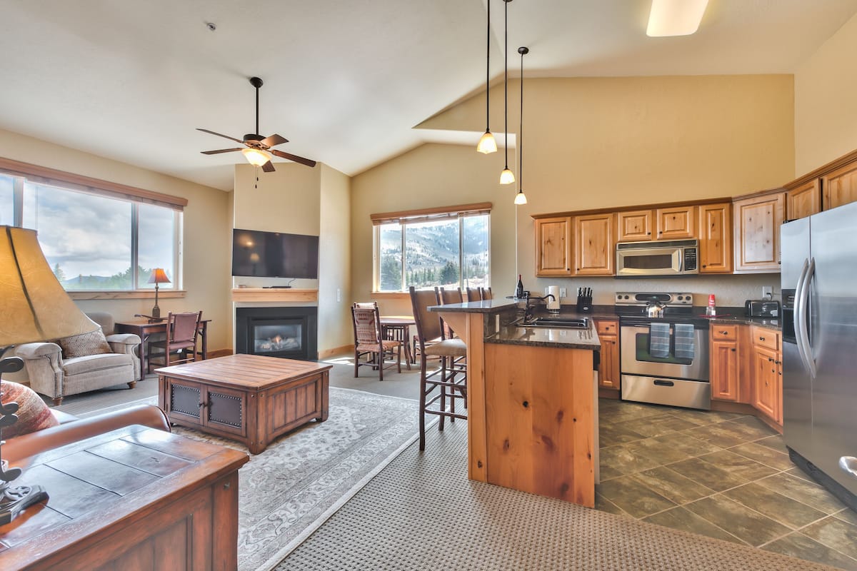 A spacious living area with a fireplace, a dining table, and a kitchen with wooden cabinets and modern appliances.