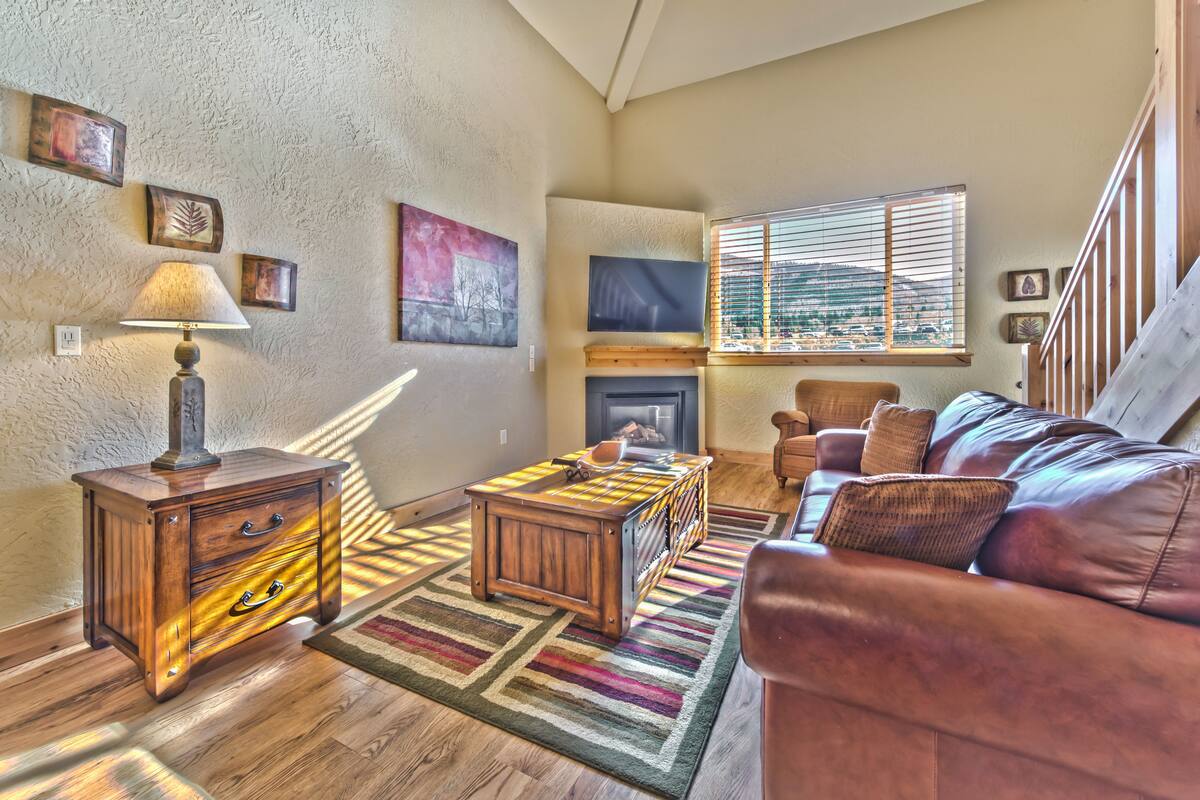 A cozy living room with a fireplace, a sofa, a coffee table, and a lamp.