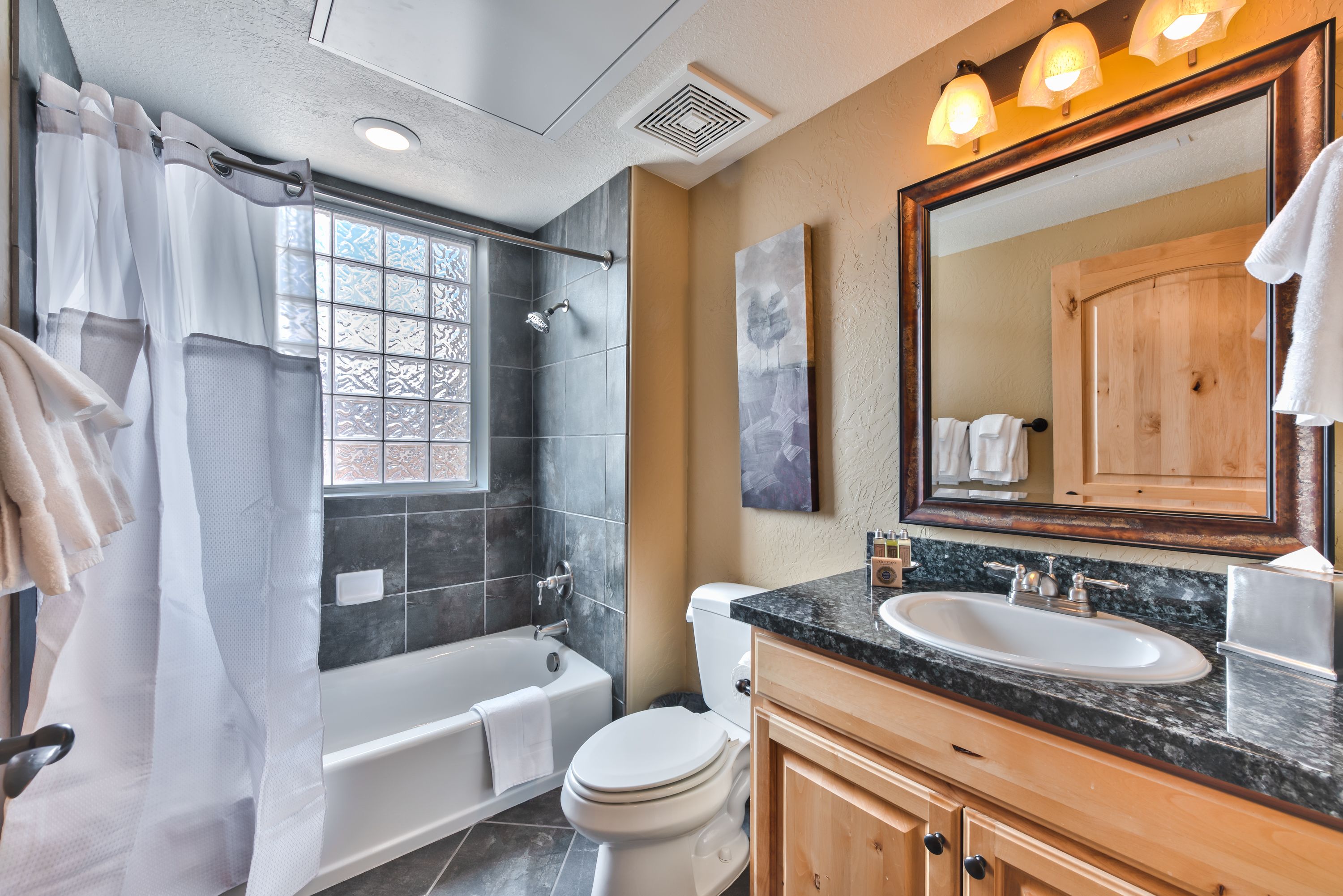A bathroom with a bathtub, toilet, sink, and a large mirror.