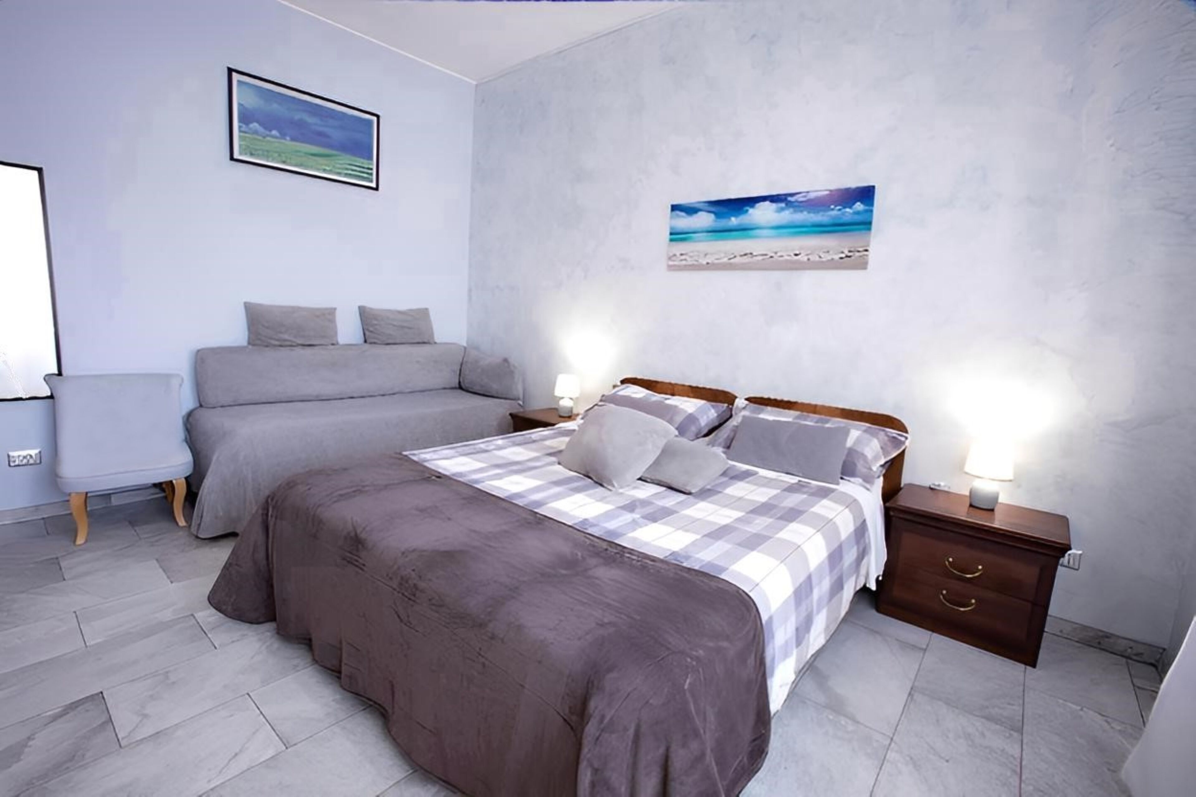 A bedroom with a large bed, a bedside table with a lamp, and a wall-mounted picture.