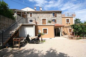 A two-story building with a stone facade, a balcony, and a motorcycle parked in front.