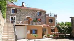 Una casa de piedra de dos pisos con balcón, garaje y un pequeño jardín.