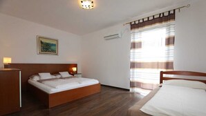 Un dormitorio con cama de madera, una mesita de noche con lámpara, una ventana con cortinas a rayas y un cuadro en la pared.