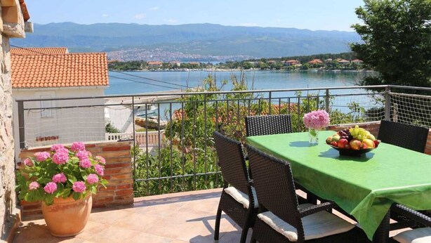 Una terraza con mesa lista para comer, con vista a un lago y montañas.