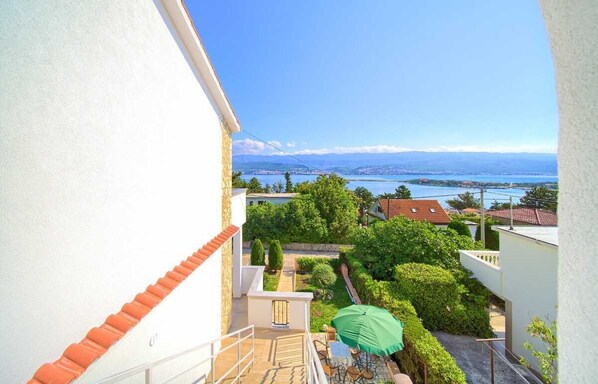 Ein Balkon mit Blick auf einen See, Grünflächen und eine ferne Stadtlandschaft.