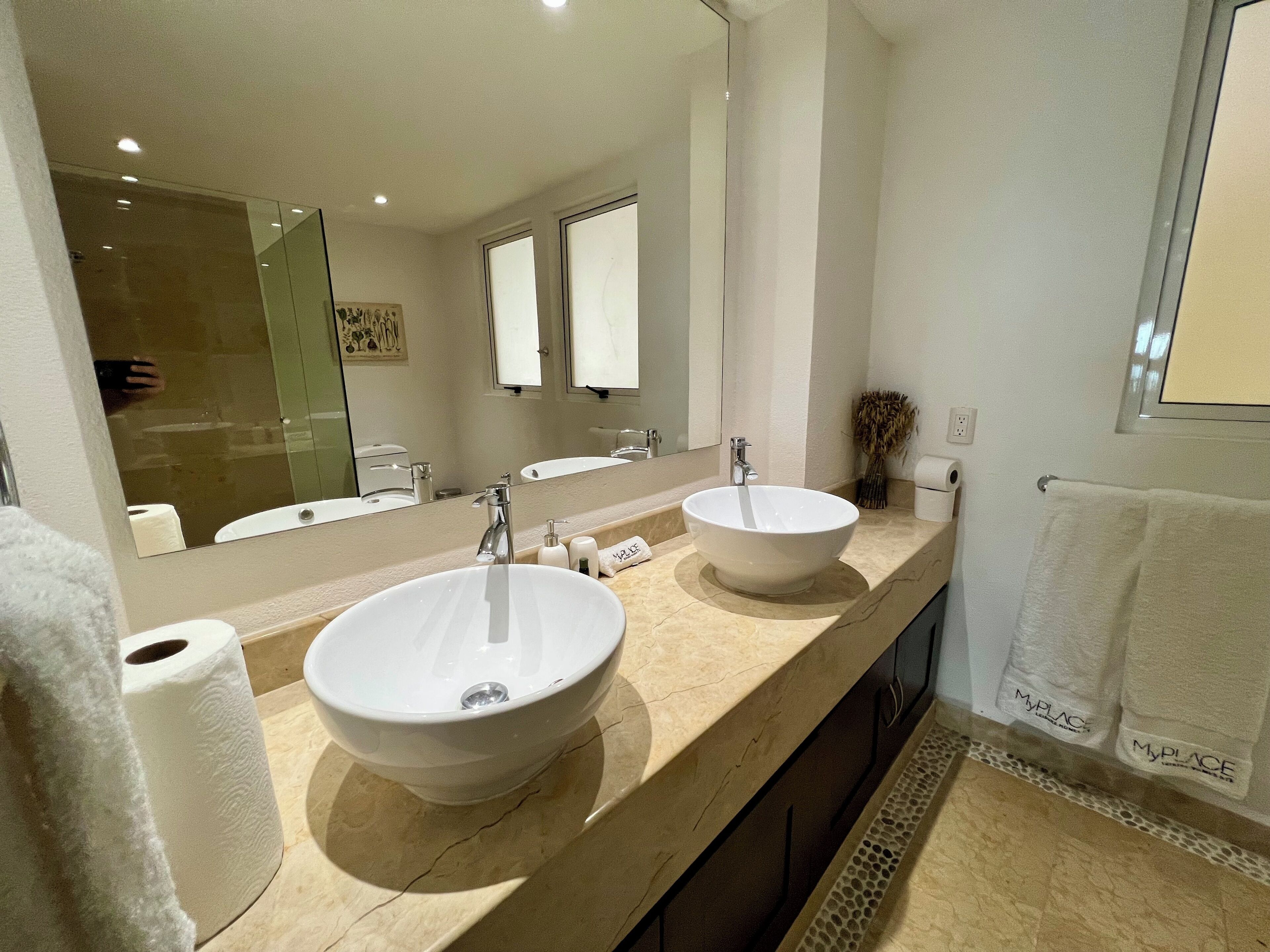 A modern bathroom with two sinks, a large mirror, and a towel rack.