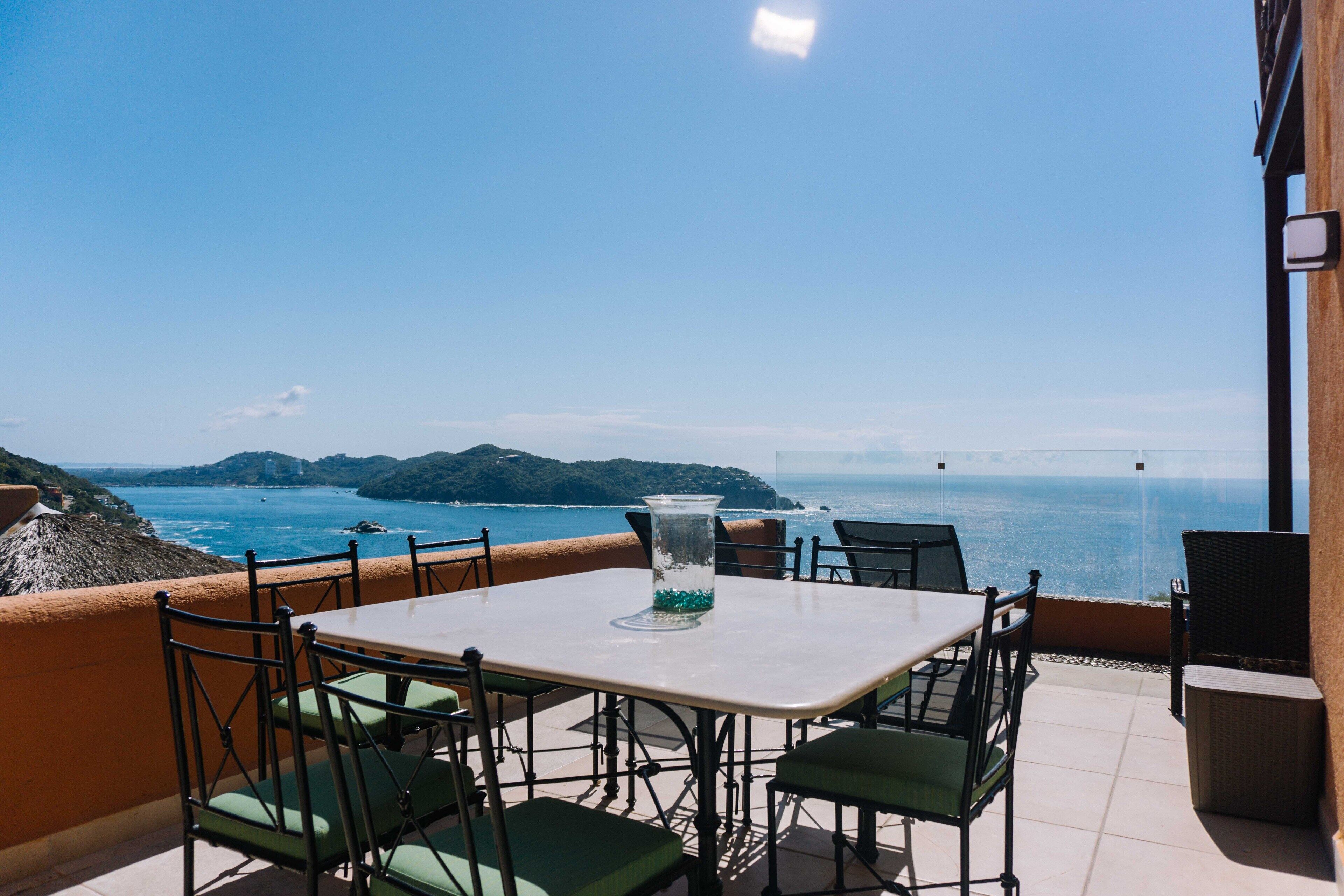 An outdoor patio with a table and chairs, overlooking a coastal view.