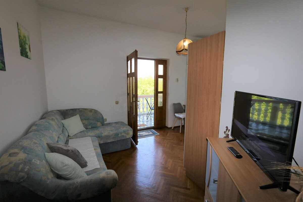 Uma sala de estar com sofá, televisão e um armário de madeira.