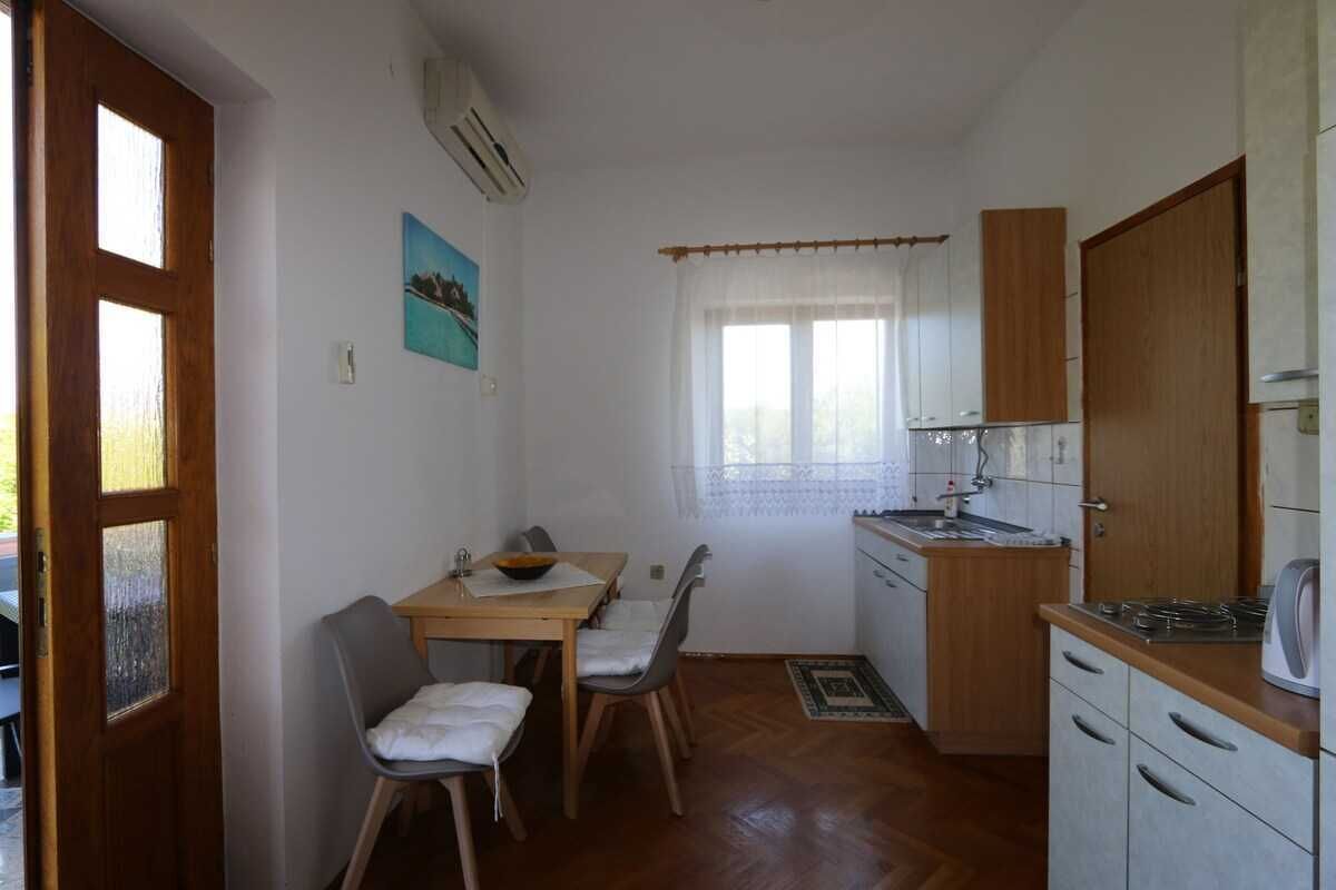 Cocina compacta con mesa, sillas, ventana con cortinas y estufa.