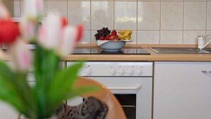 A kitchen with a white stove, a sink, and a bowl of fruit on the counter. - Apartment Padjen A2 (Silo - island Krk)