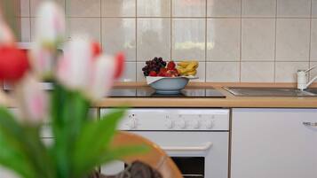 Una cocina con estufa blanca, un lavabo y un bol de fruta en la encimera.
