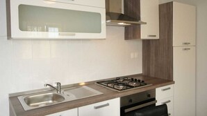 A modern kitchen with a stainless steel sink, a gas stove, white cabinets, and a wooden countertop. - Apartment Hodzic nr 3 (Silo - island Krk)