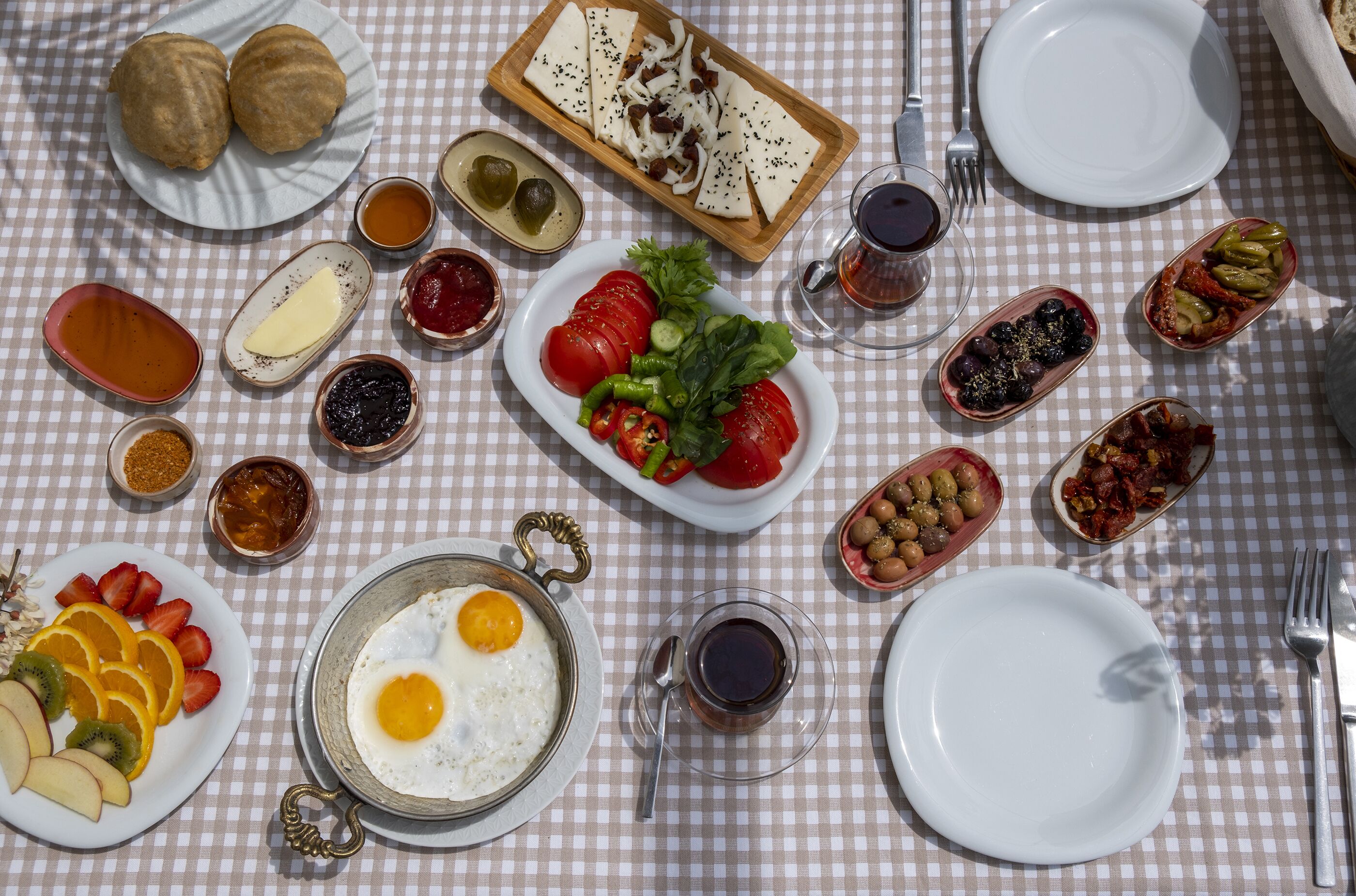 Una mesa con diversos alimentos para el desayuno, como huevos, frutas y productos de pastelería.