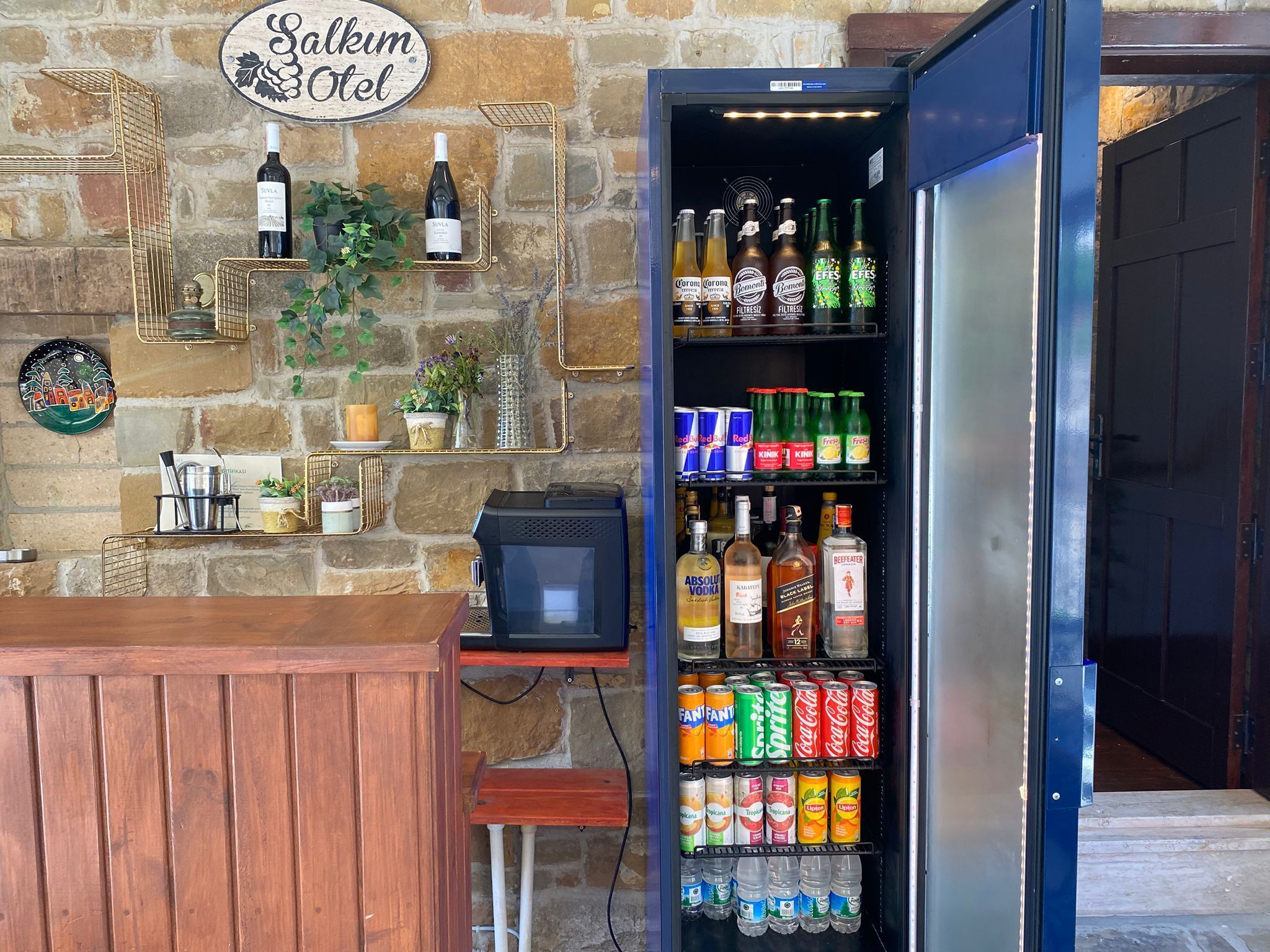Un área de bar con un refrigerador lleno de bebidas, una pared de piedra y un letrero que dice 'Salkum Hotel'.