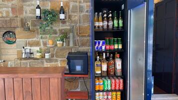 Un área de bar con un refrigerador lleno de bebidas, una pared de piedra y un letrero que dice 'Salkum Hotel'.