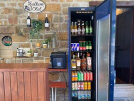 Un área de bar con un refrigerador lleno de bebidas, una pared de piedra y un letrero que dice 'Salkum Hotel'.