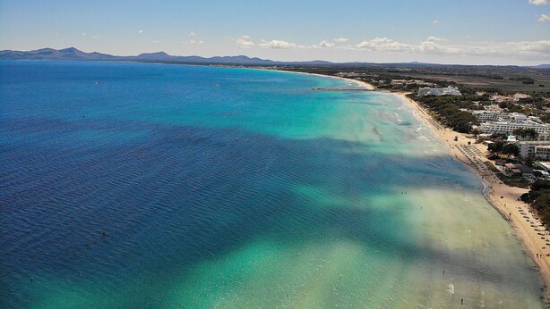 An aerial view of a coastal area with a beach, clear turquoise waters, and distant mountains. - Ca Na Coloma 145 fantastic villa with barbecue, billiards, ping pong and WiFi (Playa de Muro)