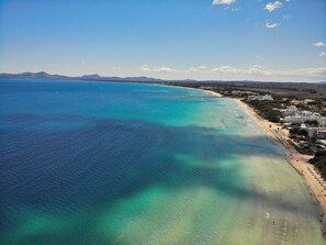 A coastal hotel with a beachfront view, including a sandy beach and a clear blue sea.