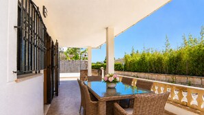 A patio with a glass table, wicker chairs, and a vase of flowers. - Ca Na Coloma 145 fantastic villa with barbecue, billiards, ping pong and WiFi (Playa de Muro)