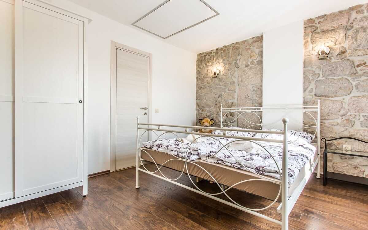 A bedroom with a metal bed frame, a stone wall, and a white door.