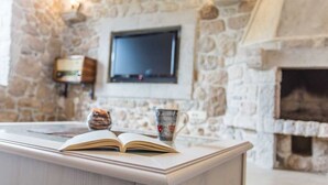 Een stenen openhaard, een flatscreen televisie erboven bevestigd, en een boek op een tafel ervoor.