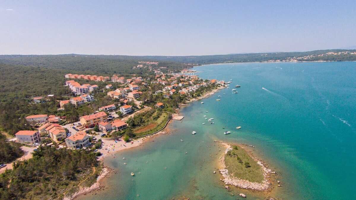 Vue aérienne d’une ville côtière avec ses bâtiments, sa plage et ses bateaux.