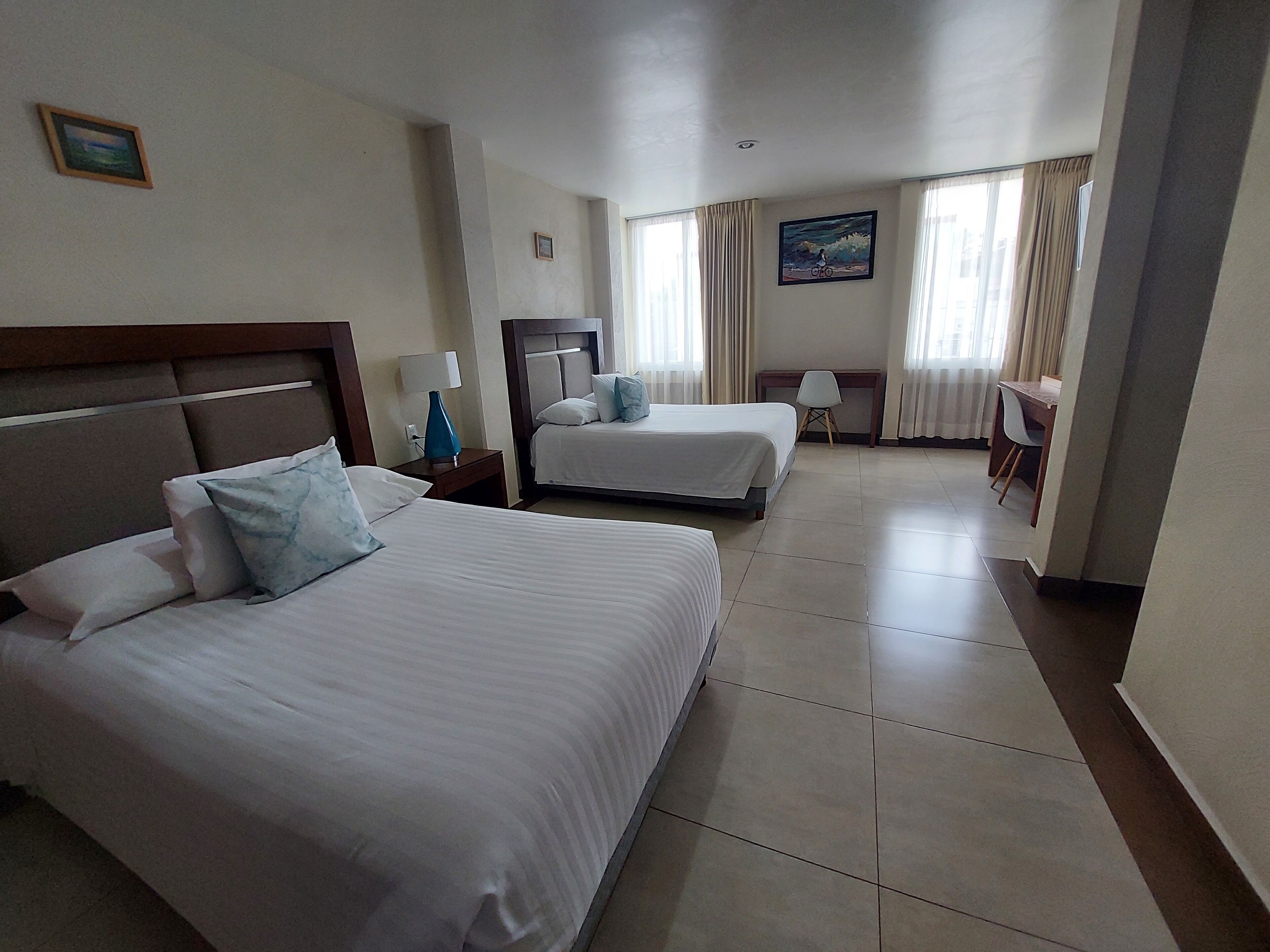 Habitación de hotel con dos camas, un escritorio y una silla.